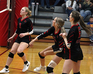 Kennedy Riener, center, has just spiked the ball at Kamiah. Also shown are Erica Schlader and Avery Kehler.
