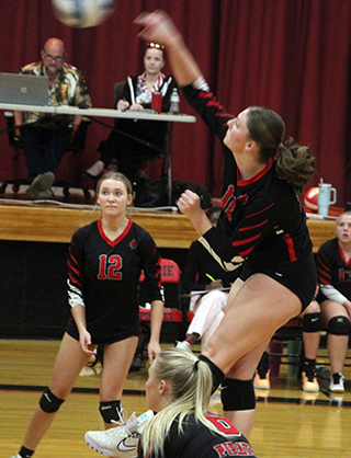 Kylie Schumacher slams the ball over against Kamiah. Also shown are Avery Riener, 12, and Mia Anderson.