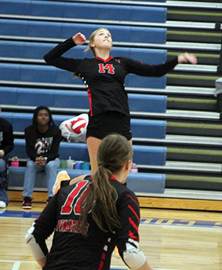 Beka Schumacher goes up for a spike against Kamiah at District. Also shown is Kylie Schumacher.