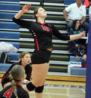 Kylie Schumacher spikes the ball against Kendrick at District. Also shown are Zoey Behler and Halee Rowland.