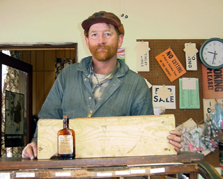 Ken Seubert with a 1906 whiskey bottle and a board with a pencil drawing that he salvaged when tearing the house down.