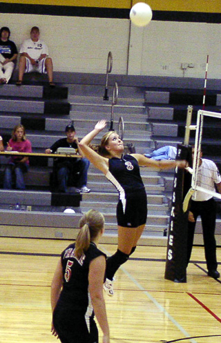 Briget Long goes up for a spike against Highland as Sarah Forsmann watches.