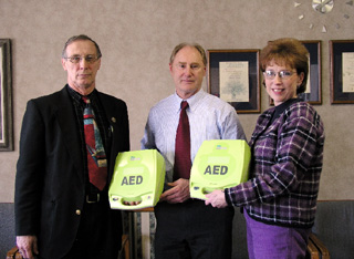 Theresa Uptmor presents Automated External Defibrillators (AEDs) from St Mary's Hospital for use in local schools to the principals of Highland and Prairie High Schools.