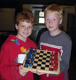 Brock Heath and Silas Whitley (winner of the 6th grade chess competition) holding the chess pieces designed and made by Brock Heath.