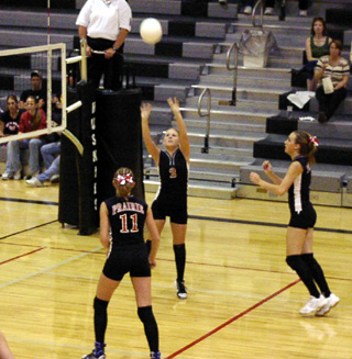 Lindsey Crea sets the ball as Ashley Schaeffer gets ready for the spike. At right is Randi Schumacher.