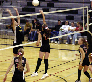 Tiffany Schaeffer guides her spike away from the blocker as Kylie Uhlorn, left, and Lindsey Crea look on.