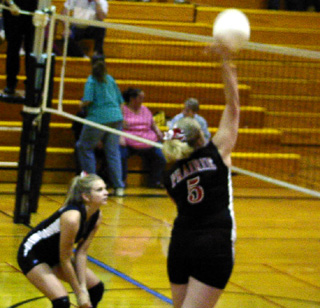 Sarah Forsmann spikes the ball while Carolyn Sonnen is ready for a possible block.