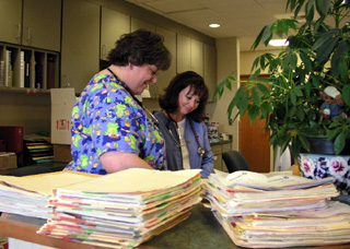 Shari Kuther, RN and Debbie Christopherson, RN, review some of the patient charts for scheduled patients at the Cottonwood clinic.