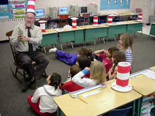Principal Greg Deiss reads to 1st graders while where a Cat In the Hat stovepipe hat.