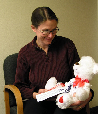 Barb Michels holds a teddy bear with the saying Fragile, handle with care on his t-shirt.