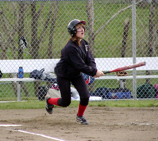 Alli Holthaus watches the flight of the ball as she heads for first.
