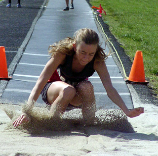 Gina Holthaus closes her eyes as she kicks up sand in the long jump pit. She won the event Saturday at Kamiah.