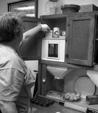 Sandy Pearsall selects an artifact from the exhibit of an early prairie kitchen at The Historical Museum.