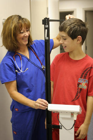 Nurse Debbie Christopherson weighs a young athlete during a sports physical.