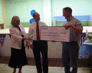 Ferdinand Mayor Paul Schmidt, right, receives a check representing a $150,000 grant to help renovate the Ferdinand Gym from Gov. and Mrs. Jim Risch.