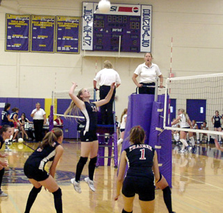 Kylie Uhlorn goes up for a spike. Also shown are Kim Schaeffer and Randi Schumacher.
