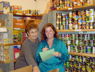 Krystyne Bahlman, right, keeps a SMHC Food Bank inventory sheet while Irma Tacke unloads a donation box and Merna Gehring (behind) stocks the shelves.