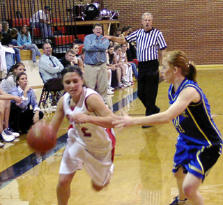 Nicole Nida dribbles past a Genesee defender as coach Steve Wilson shouts instructions in the background.