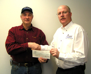 Tom Gehring receives a $500 check in recognition of outstanding community service performed by local Primeland employees.