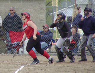 Hilaree VanderPas, the catcher and umpire all watch her long drive head for the fence. It hit the base of the fence on the fly for a double.