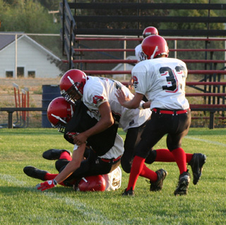 David Sigler gets tackled by a pair of white team defenders.