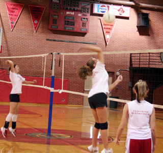 Kim Schaeffer spikes the ball during a drill in practice. Sam Frei is at left while Alli Holthaus is at right.