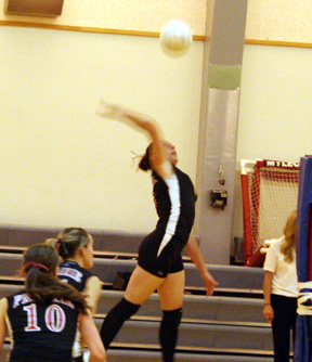 Kaylee Uhlenkott goes high for a spike. Also shown are Tiffany Schaeffer and Alli Holthaus.