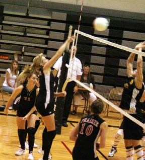 Chelsea Long spikes the ball at Highland. At left is Alli Holthaus and at right is Tiffany Schaeffer.