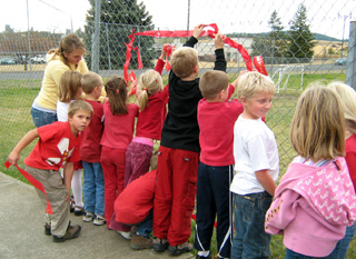 Christa Wilson and Prairie Elementary students put up ribbons in the chain link fence at the school to spell out Drug Free.