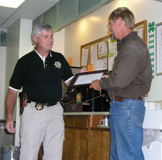 Idaho County Sheriff, Larry Dasenbrock, presents a certificate to Tom Schumacher, St. Marys Hospital maintenance crew for his bravery in assisting a jailer whod been injured by an inmate patient.