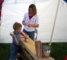 Wes Munger tries to knock over a stack of bottles in the baseball toss booth at the Kids Carnival. The Kids Carnival was a new event this year.