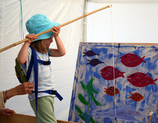 A young lady fishes for a prize in one of the Kids Carnival booths.