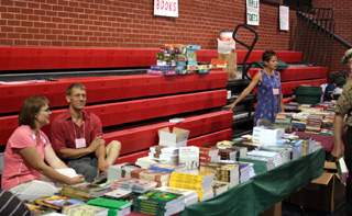 Local volunteers donated many hours to manning booths and events at the Raspberry Festival. Shown are Vic and Theresa Lustig and Pollyanna Candalot at the book sale booths in the PHS gym.