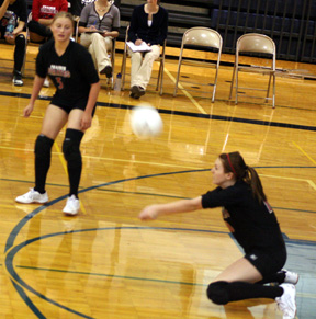 Kayla Johnson digs up a serve. At left is Leora Laurino.