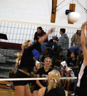 Chelsea Long spikes the ball against Deary. In the background is Brianne Stubbers.