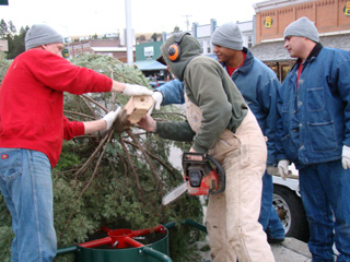 NICI offender work crew helps Don Connolly prepare the base of the tree for the stand that was donated by Wimer Machine Shop.