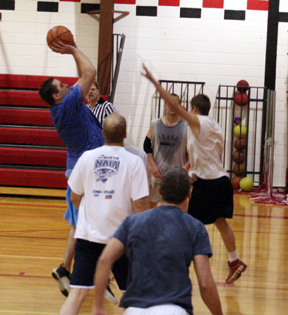 Justin Forsmann shoots a jumper in the men's alumni game. Others shown from left are Adam Forsmann, Glenn Poxleitner (gray shirt), Mat Forsmann (blue shirt) and Kenneth Enneking.