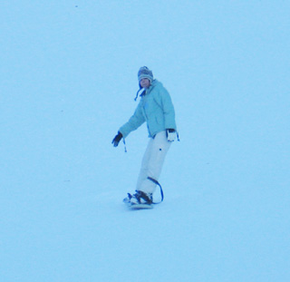 A snowboarder makes their way down the hill.