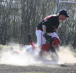 Seth Guyer gets a face full of dirt as he scores from third on a passed ball.