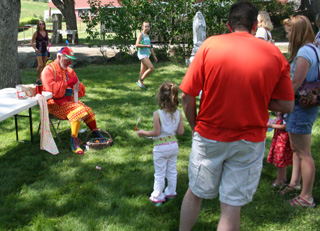 A clown was making balloon animals in the kids carnival area.