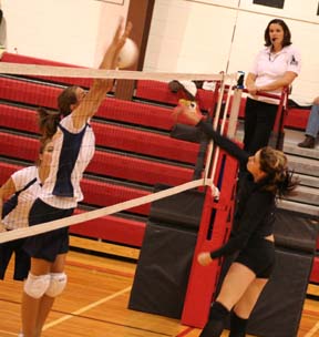 Sam Poxleitner spikes the ball past the block attempt of Savanah Prigge. at left is Jamie Chmelik.