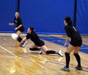 Casey Bruegeman digs up a C.V. serve as Meaghan Bruner and Francesca Johnson watch.