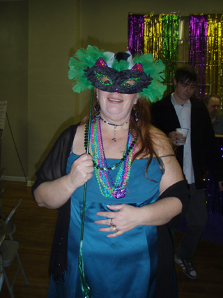 A Mardi Gras party goer gets into the spirit of things.  Her mask can be used again at next year’s event.