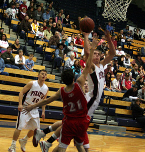 Devin Schmidt contorts his way around a defender as he puts up a shot. In the back is Kyle Holthaus.