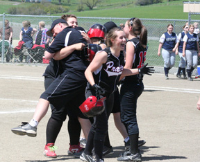 Prairie coach Jeff Martin hugs Hilaree VanderPas after her 3-run double won the District championship game against Genesee. Also shown are Megan Sigler and Meaghan Bruner.