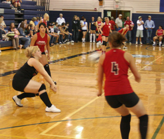 Demetria Riener digs up a serve as Francesca Johnson and Megan Sigler watch.