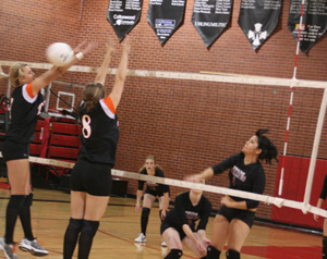 Fran Johnson spikes the ball past Troys blockers. Also shown are Tanna Schlader and Kayla Johnson.