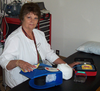 Karla Enneking will teach a free CPR/AED class for the public on September 22.  Enrollment is limited.  Register by calling SMHC, 962-3251.  She is pictured with an AED and one of the mannikins that will be used in the class.