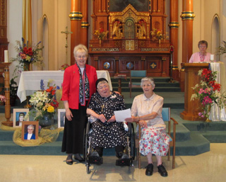 Prioress Sister Clarissa Goeckner with Sister Petronilla Lieser (center) and her sister, Sister Bernard Lieser, who holds up the Profession vows that Sister Petronilla renewed in the presence of her community.
