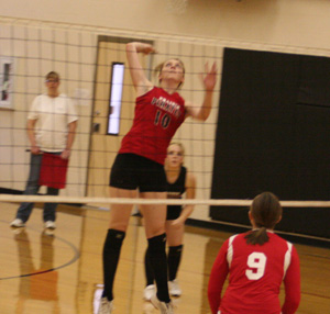 Kayla Johnson winds up for a kill against St. John-Endicott. Behind her is Demetria Riener. At far right is Sam Poxleitner.